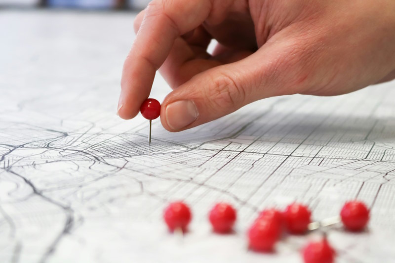 Person placing red pins in a road map